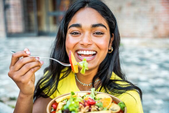 Portrait of young happy woman eating healthy