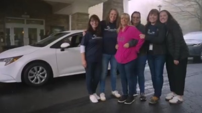 North Carolina resident Sherri Hughes (pink sweatshirt) poses with volunteers with Samaritan's Purse after she was gifted a new car in the aftermath of Hurricane Helene. 