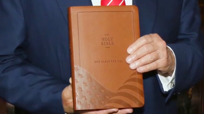 President Donald Trump holds up a 'God Bless the USA Bible' in a video. It is on sale for $59.99 and features the King James Version along with America's founding documents.