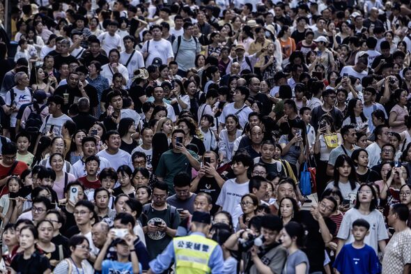A police officer faces a large crowd of tourists