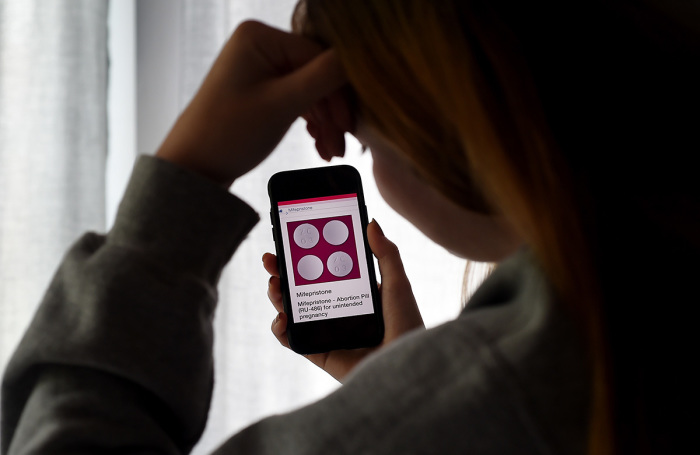 In this photo illustration, a person looks at an Abortion Pill (RU-486) for unintended pregnancy from Mifepristone displayed on a smartphone on May 8, 2020, in Arlington, Virginia.