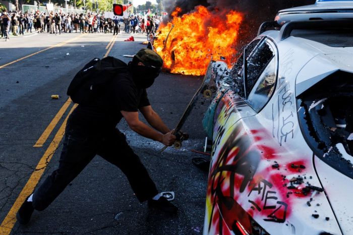 This picture taken on June 8, 2025 shows a protestor shattering the window of a Waymo vehicle during a demonstration following federal immigration operations in Los Angeles. Demonstrators torched cars and scuffled with security forces in Los Angeles on June 8, as police kept protestors away from the National Guard troops President Donald Trump sent to the streets of the second biggest US city.