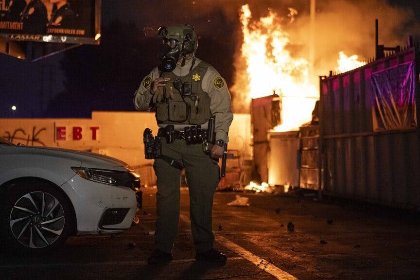 PARAMOUNT, CALIFORNIA - JUNE 7: A shopping cart is seen on fire as protesters shield themselves from flash bang grenades shot by the Sheriffs Department after Immigration and Customs Enforcement (ICE) agents and Department of Homeland Security (DHS) officers made raids of illegal immigrants in Paramount, California, United States on June 7, 2025. (Photo by Jon Putman/Anadolu via Getty Images)