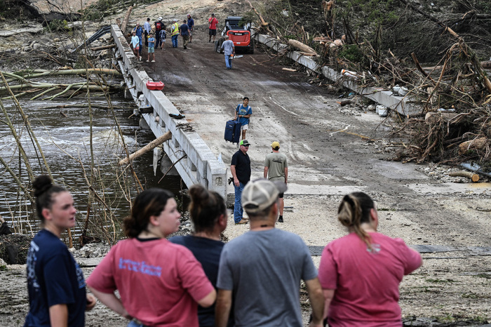 People look on as law enforcement and volunteers continue to search for missing people near Camp Mystic, the site of where at least 20 girls went missing after flash flooding in Hunt, Texas, on July 5, 2025. Rescuers were on Saturday searching for more than 20 girls missing from a riverside summer camp in Texas, after torrential rains caused devastating flooding that killed at least 27 people -- with more rain on the way. 'So far, we've evacuated over 850 uninjured people, eight injured people and have recovered 27 deceased fatalities at this time. Of these 27, 18 are adults, nine are children,' said Kerr Country Sheriff Larry Leitha on July 5.