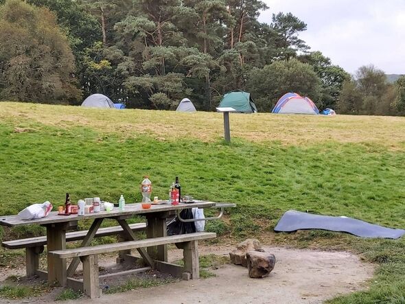 Picnic litter left on a table at Llyn Geirionydd with tents pitched illegally in the background
