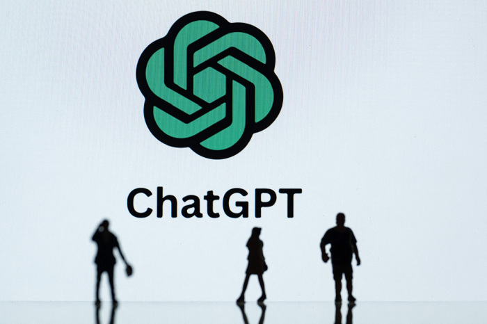 This photograph taken in Mulhouse, eastern France on October 19, 2023, shows figurines next to the ChatGPT logo.