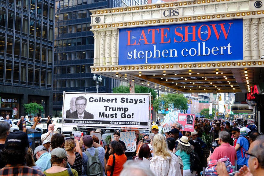 People participate in a protest titled 'Colbert stays! Trump must go!' outside the Ed Sullivan Theater in New York City on July 21, 2025. "The Late Show with Stephen Colbert," a staple of late-night US television, will end in 2026, the CBS network said, days after the comedian blasted parent company Paramount's $16 million settlement with President Donald Trump as "a big fat bribe." (Photo by CHARLY TRIBALLEAU / AFP) (Photo by CHARLY TRIBALLEAU/AFP via Getty Images)