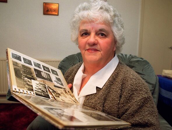 woman looking at camera while holding photo album