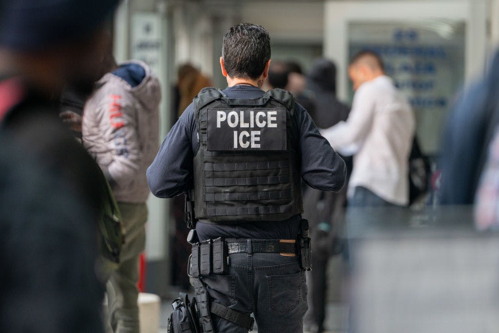 NEW YORK, NEW YORK - JUNE 6: An ICE agent monitors hundreds of asylum seekers being processed upon entering the Jacob K. Javits Federal Building on June 6, 2023 in New York City. New York City has provided sanctuary to over 46,000 asylum seekers since 2013, when the city passed a law prohibiting city agencies from cooperating with federal immigration enforcement agencies unless there is a warrant for the person's arrest.