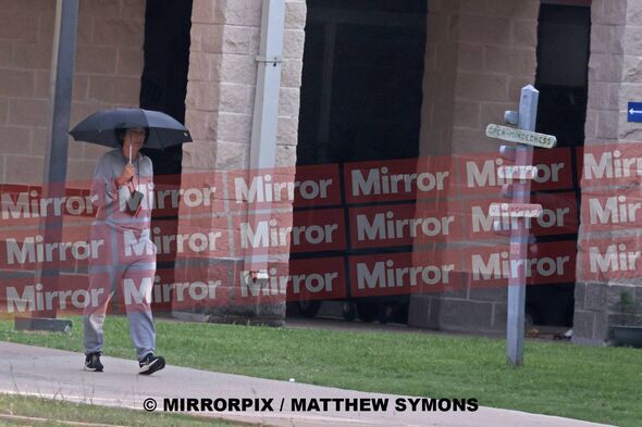 Ghislaine Maxwell holds her umbrella as she walks on prison grounds