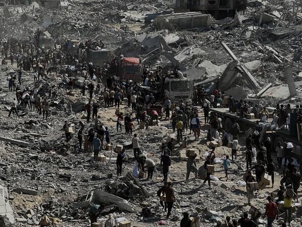 Hundreds of people carrying supplies amid the destroyed city of Khan Yunis