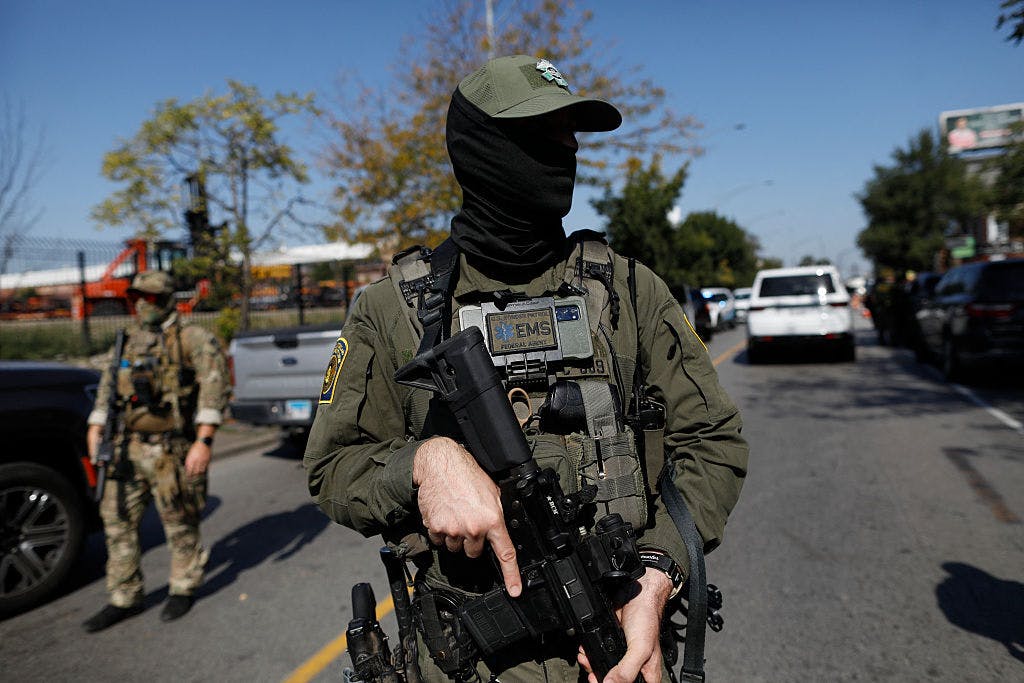 A masked US Customs and Border Protection (CBP) Border Patrol agent is seen as residents of Chicago's Brighton Park neighborhood confront law enforcement at a gas station after Immigration and Customs Enforcement (ICE) agents allegedly detained an unidentified man riding in his car, in Chicago, Illinois, on October 4, 2025. US President Donald Trump, who campaigned on a pledge to deport large numbers of migrants, has encouraged authorities to be more aggressive as he seeks to hit his widely reported target of one million deportations annually. (Photo by OCTAVIO JONES / AFP)