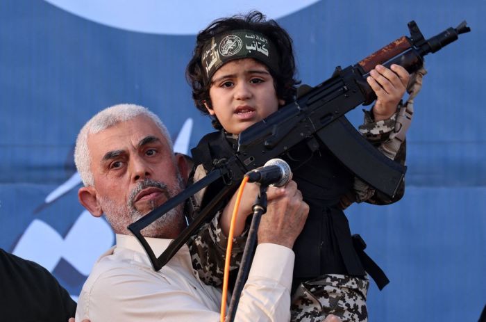 Hamas leader Yahya Sinwar holds the child of an Al-Qassam Brigades fighter, who was killed in the recent fighting with Israel, with a Kalashnikov rifle in his hand during a rally in Gaza City on May 24, 2021.