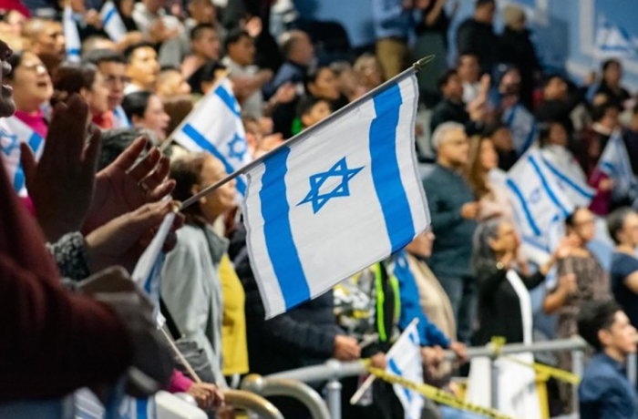 Hundreds of attendees raise Israeli flags in the auditorium of Breath of Life Church in Queens, New York, during the