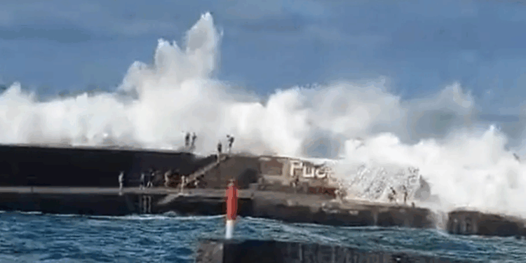 Tourist dead and nine injured after powerful wave drags swimmers out to sea at popular holiday hotspot