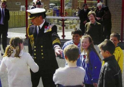 Children in playground chat to man in naval uniform Children in playground chat to man in naval uniform
