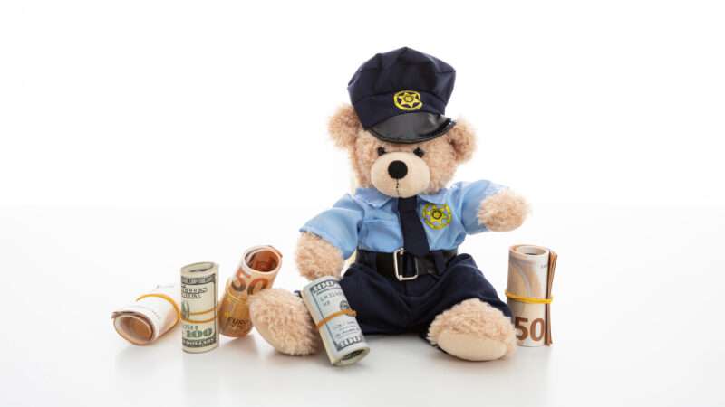 Policeman teddy bear surrounded by cash and coins. | Rawf88 | Dreamstime.com