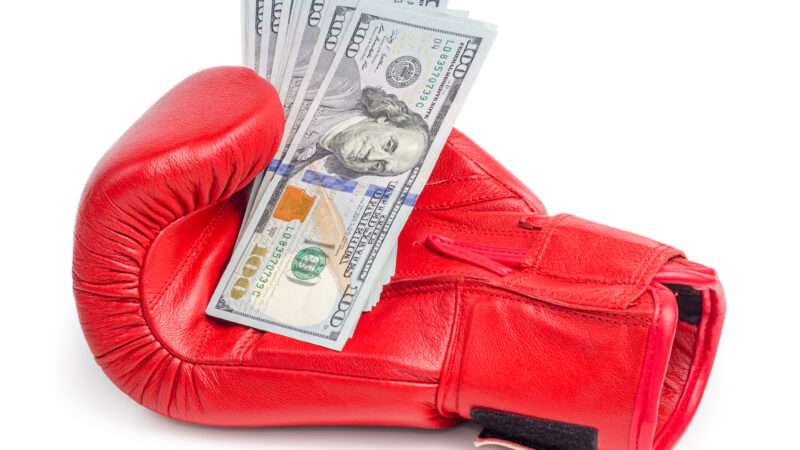 A boxing glove with a handful of U.S. $100 bills. | Zaclurs | Dreamstime.com