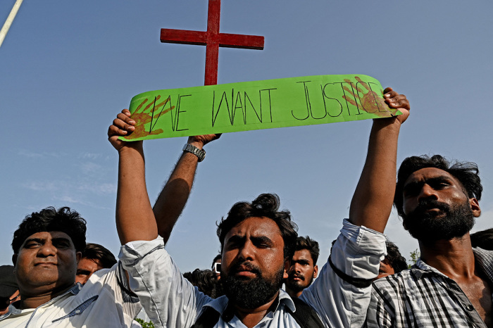 Christians hold the holy cross and a placard during a protest in Islamabad on Aug. 20, 2023, to condemn the attacks on churches in Pakistan. 