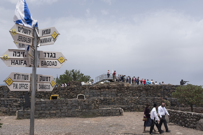 Ultra Orthodox Jews and tourists gather next to signs pointing out distances to different cities on Mount Bental next to the Syrian border in the Israeli-annexed Golan Heights on May 10, 2018.