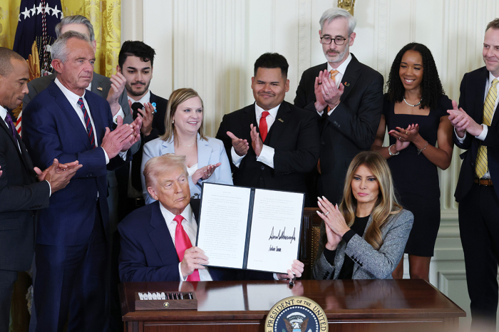 U.S. President Donald Trump, joined by first lady Melania Trump, members of his administration and foster care advocates, signs the