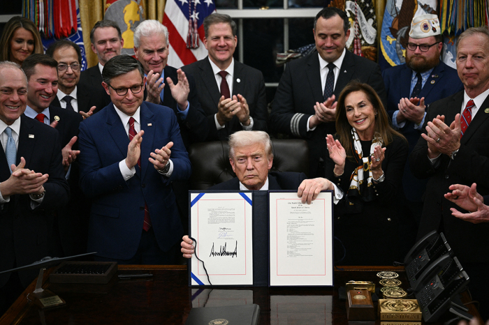 U.S. President Donald Trump shows the signed bill package to re-open the federal government in the Oval Office of the White House in Washington, D.C., on Nov. 12, 2025.