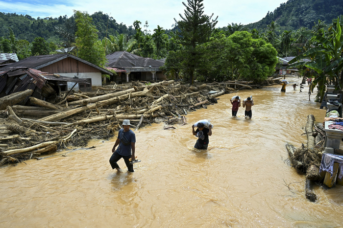 People wade through the floodwater in the aftermath of flash floods at Tukka village, Central Tapanuli, North Sumatra province, on Dec. 2, 2025. The death toll from floods and landslides that have struck Indonesia's Sumatra island since last week has risen to 712, the National Disaster Management Agency said on Dec. 2.
