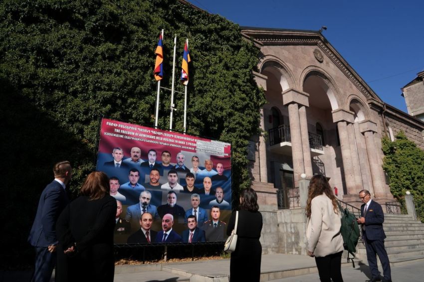 A delegation from Save Armenia looks at a sign showing the 23 Armenian hostages held by the Azerbaijan government in Baku outside of a building in Yerevan, Armenia, that houses the government-in-exile of the Republic of Artsakh, on Sept. 24, 2025. 
