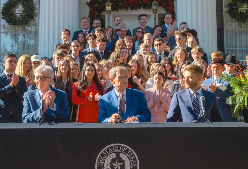 Texas Gov. Greg Abbott (center) is joined by  Lt. Gov. Dan Patrick and Texas Education Agency (TEA) Commissioner Mike Morath along with TPUSA supporters at the Governor's Mansion in Austin, Texas on Dec. 8, 2025.