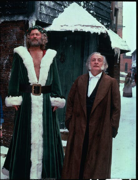 English actor Edward Woodward (left) as Christmas Present and American actor George C. Scott (1927 - 1999) as Ebenezer Scrooge in a television adaptation of the 1843 Charles Dickens short story 'A Christmas Carol,' 1984. (Photo by CBS Photo Archive/Getty Images)