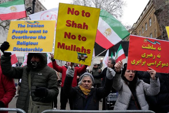 A group of individuals participating in a protest, holding various signs with written messages. The signs display phrases such a