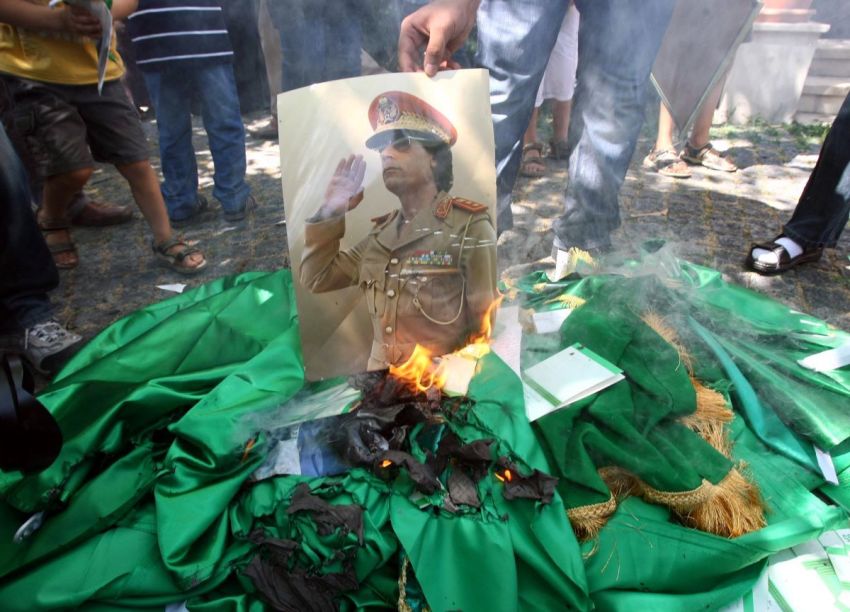 Demonstrators set fire to a poster of Libyan leader Muammar Gaddafi, copies of his book and Libyan flags during a protest against Kadhafi outside the Libyan embassy in Ankara on August 22, 2011.