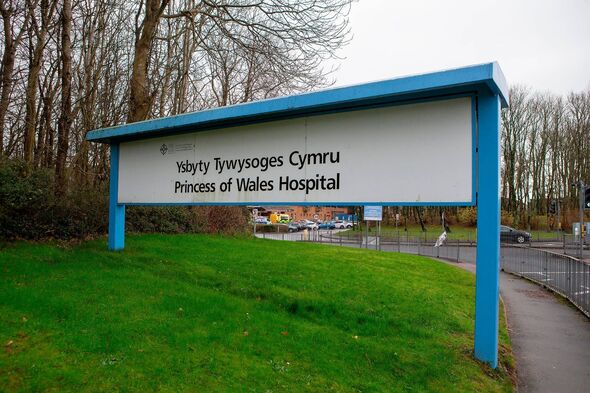 An exterior signboard situated on a grassy area displays the name of a medical facility, with a blue border and white background