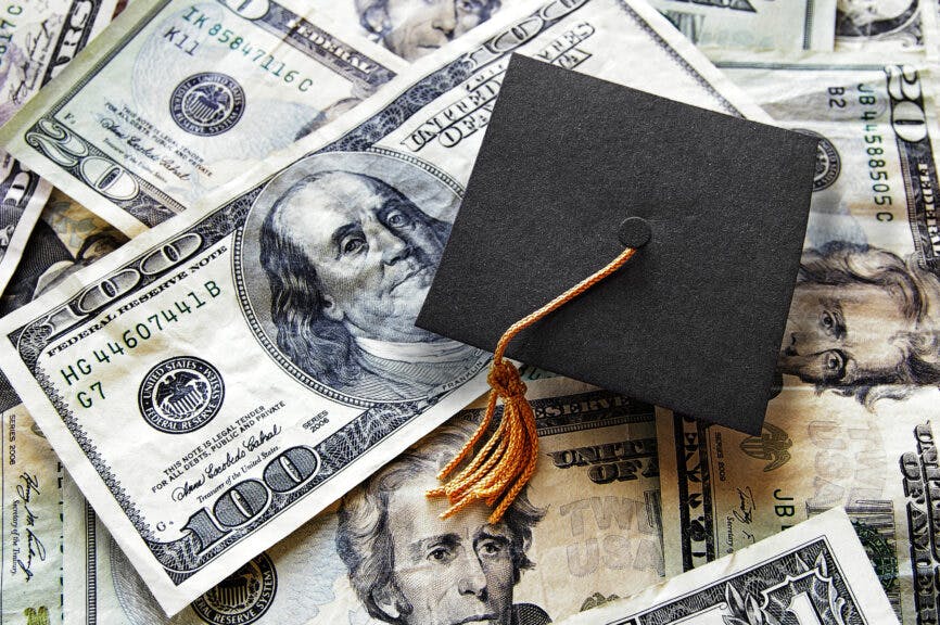 zimmytws. Getty Images. Miniature graduation cap on hundred dollar bills.