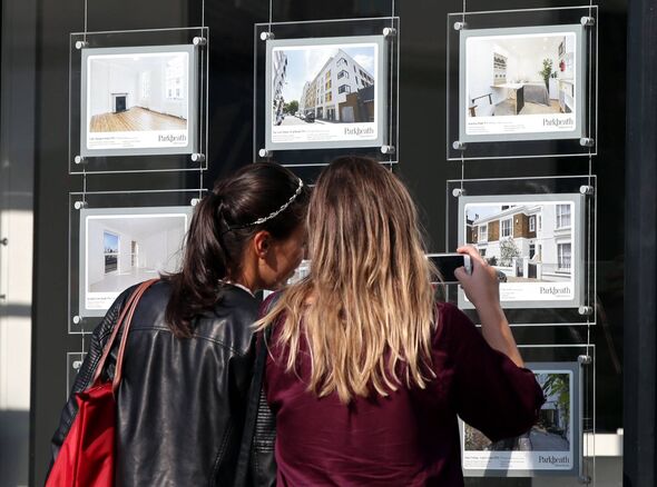 A couple of women studying the house price signs in an estate agents window