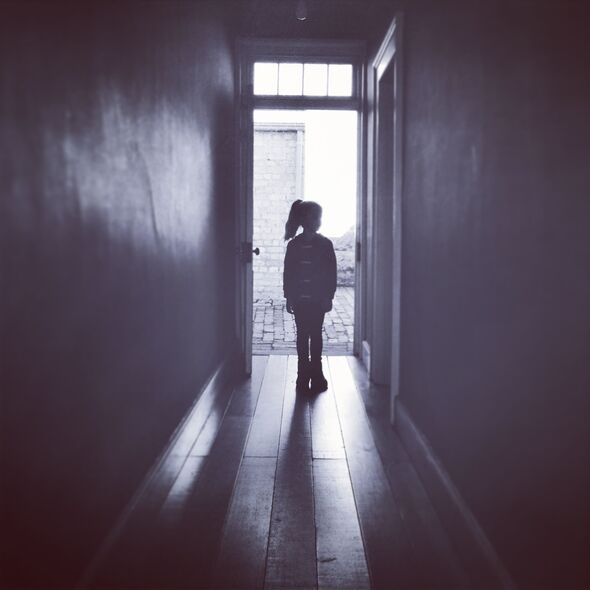 Silhouette of child standing alone in hallway