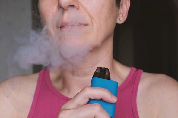 woman exhaling dense vapor through nose while holding blue vape device