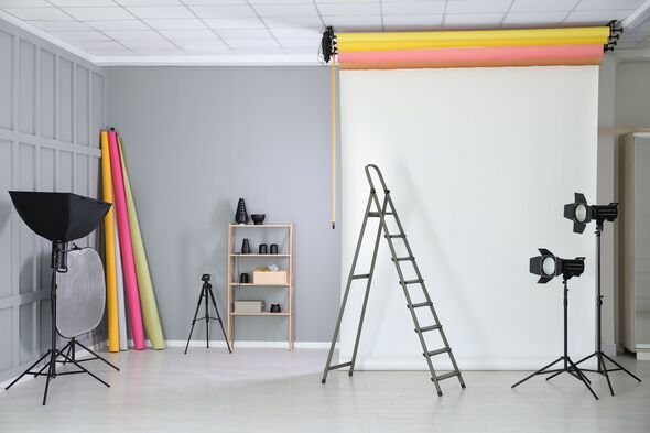 White photo background, ladder and professional lighting equipment in modern studio