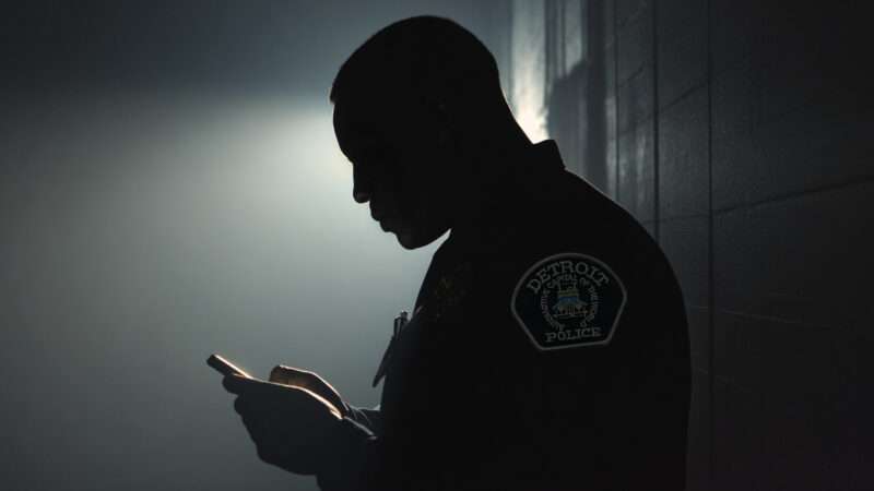 A Detroit Police officer, in shadow, scrolls through a cell phone. | Illustration: Midjourney/Wikimedia Commons