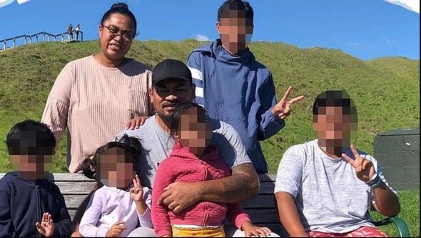 A group of individuals, possibly a family, is gathered in an outdoor setting, seated on a bench surrounded by a grassy landscape A group of individuals, possibly a family, is gathered in an outdoor setting, seated on a bench surrounded by a grassy landscape