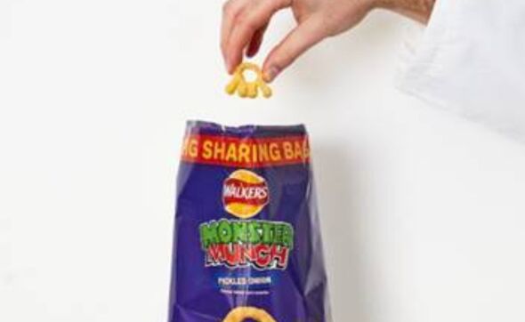A man holding a sharing bag of Walker's Monster Munch crisps