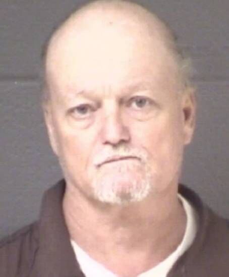 An image depicting an older individual with a bald head and a prominent beard. The person appears to be posing for a photograph 