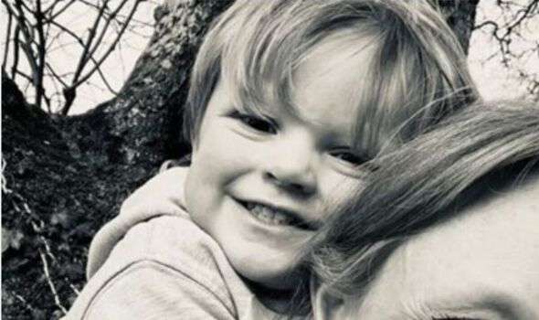 Rufus Davies smiles on a woman's back