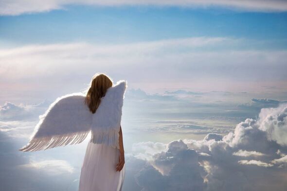 An individual dressed in a white garment, resembling an angel, with wings spread wide, stands atop a cloud, gazing towards the h