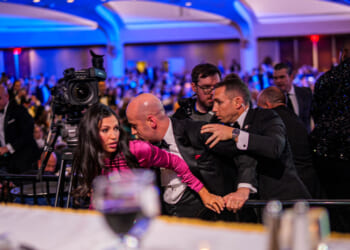 White House Deputy Chief of Staff Steven Miller protects his wife as agents try to usher him out of White House Correspondents' Dinner.