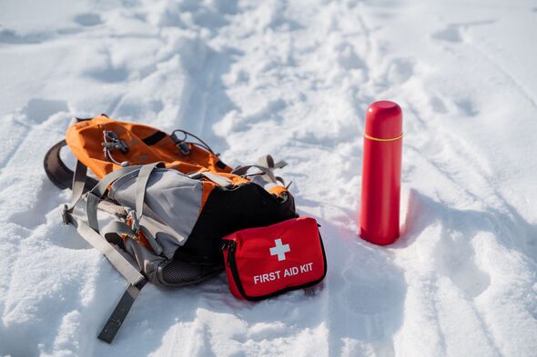 A backpack and a first aid kit can be seen resting on the snow, indicating someones preparedness for winter adventures or emergencies in the great out