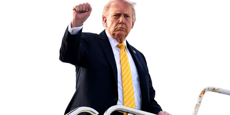 President Donald Trump raises his fist as he boards Air Force One.